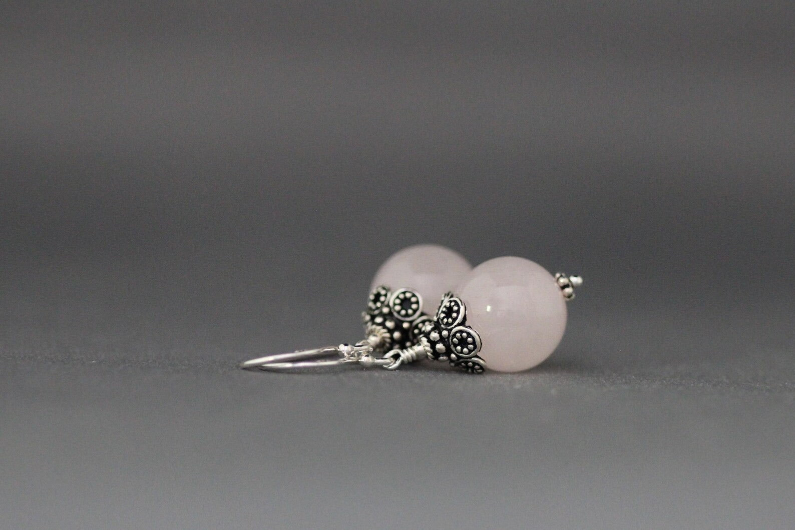 Rose quartz and silver earrings against a gray backdrop