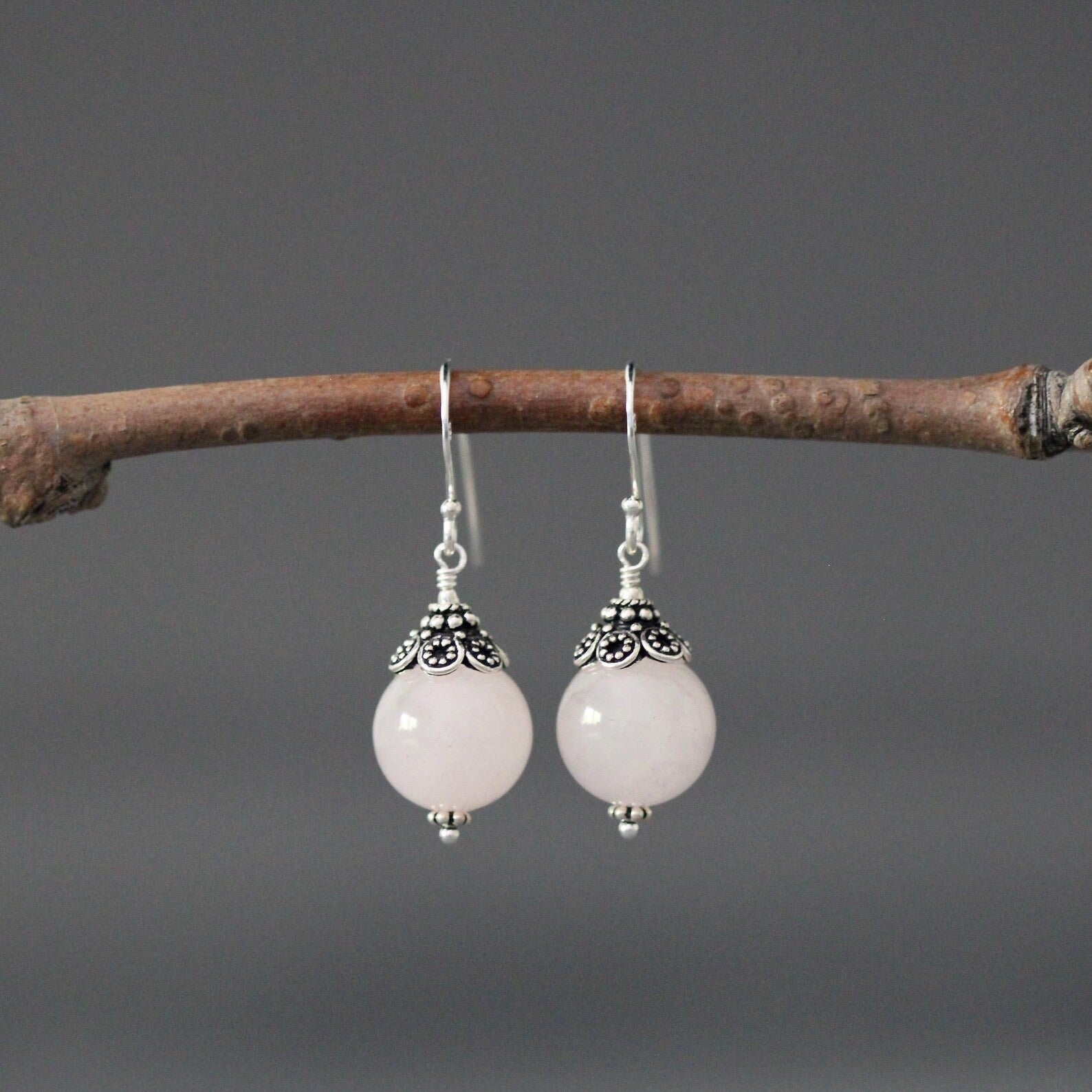 Rose quartz and silver earrings against a gray backdrop