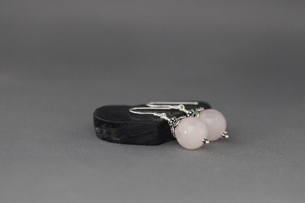Rose quartz and silver earrings against a gray backdrop