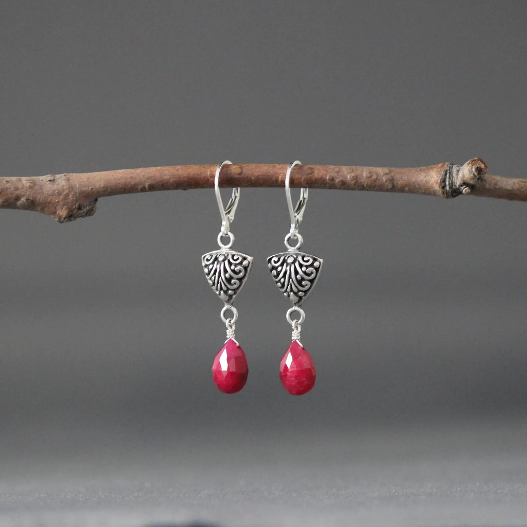 Silver Bali-style teardrop earrings with detailed caps and red teardrop gemstones