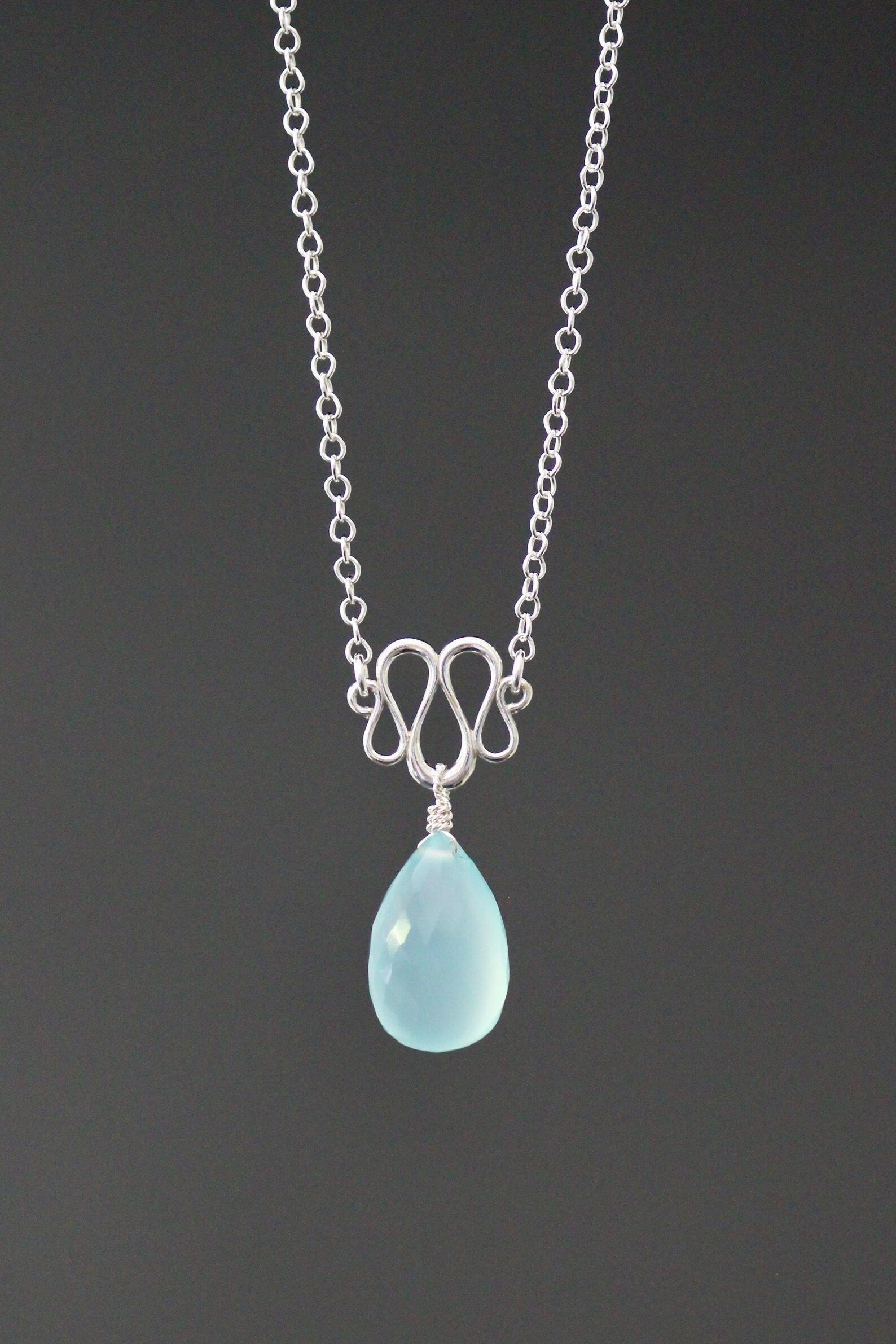 Necklace with a blue teardrop pendant on a dark background