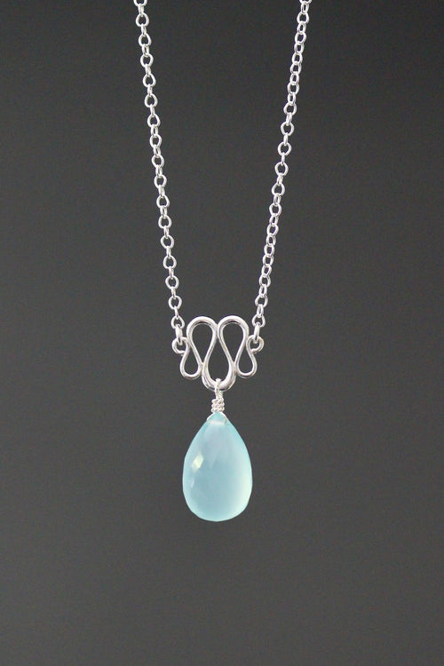 Necklace with a blue teardrop pendant on a dark background