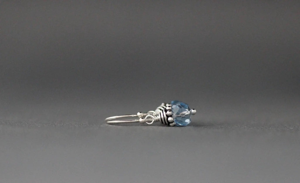 Silver earrings with a blue gemstone on a gray background