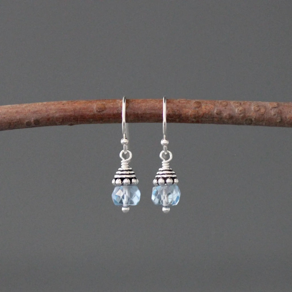 Pair of silver earrings with blue beads on a gray background