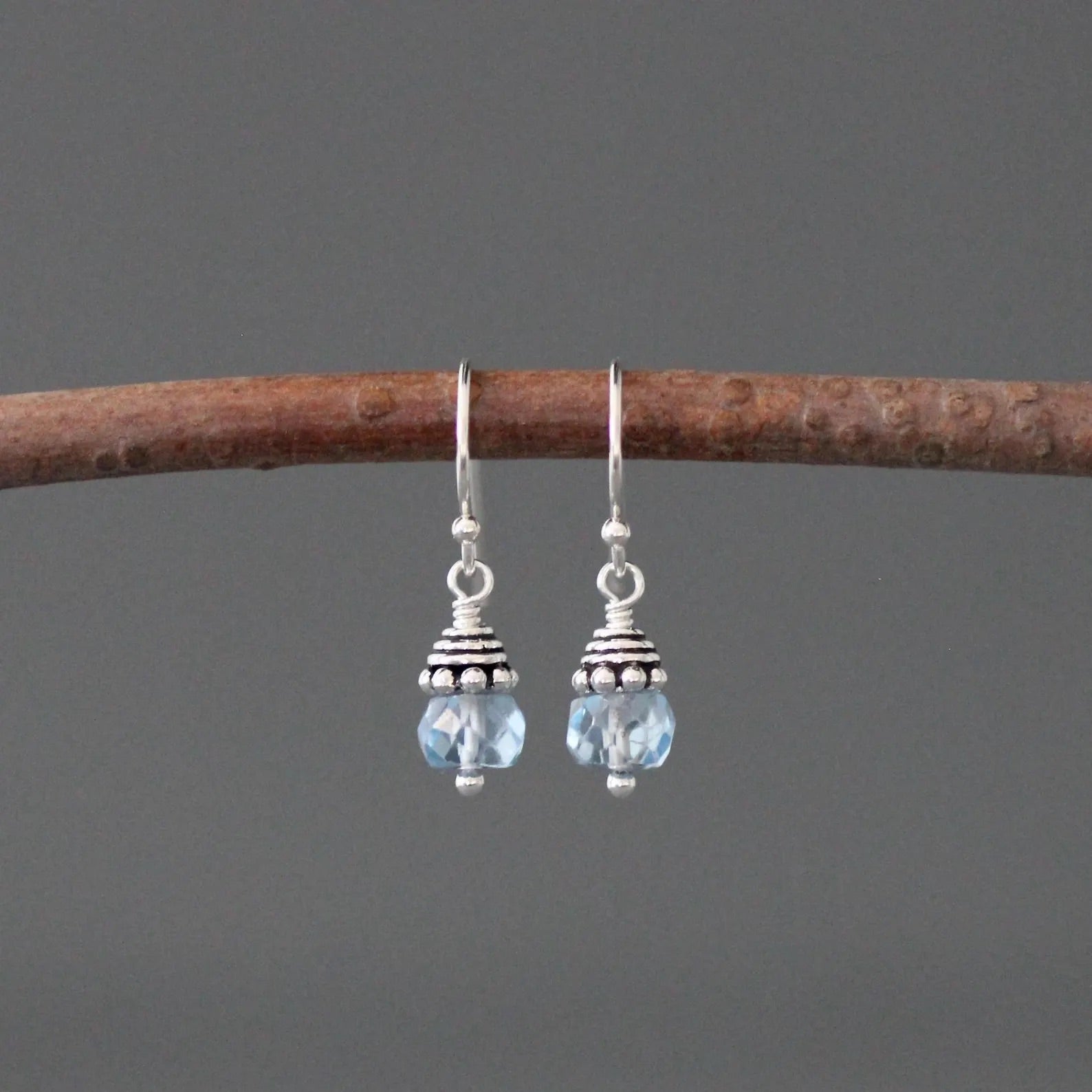 Pair of silver earrings with blue beads on a gray background