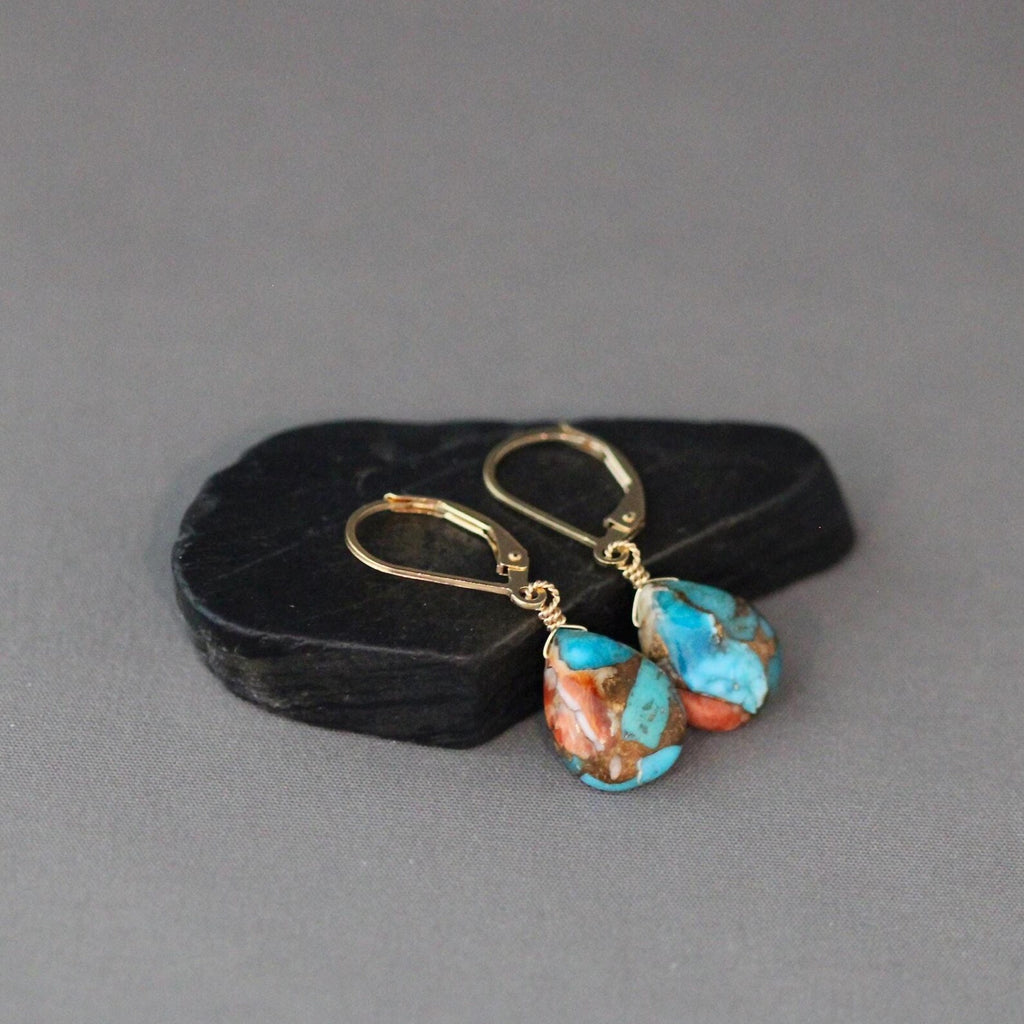 Turquoise and gold earrings on a gray background