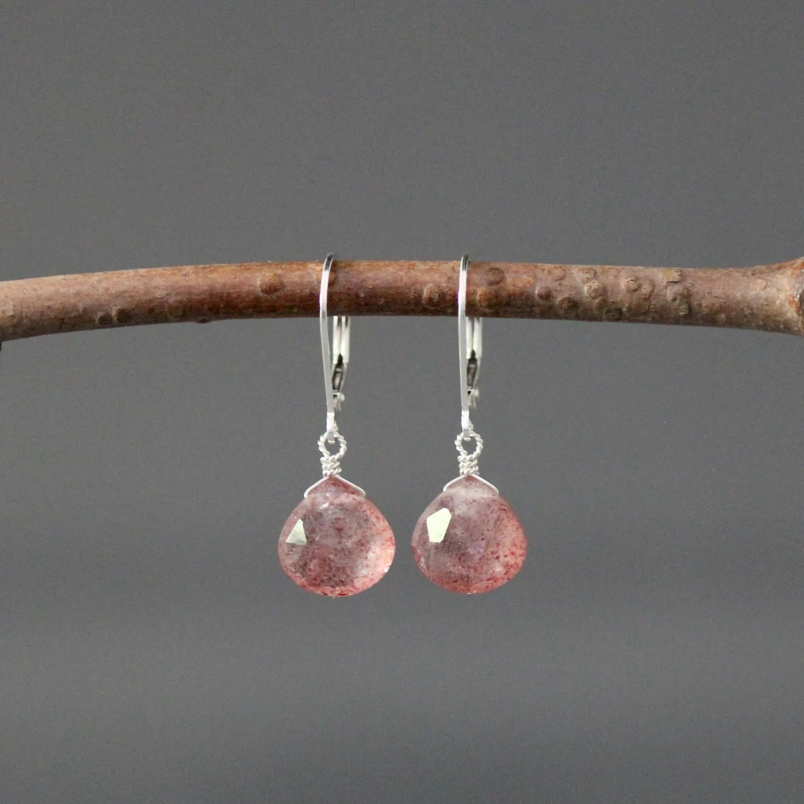Strawberry quartz and silver earrings against a gray backdrop