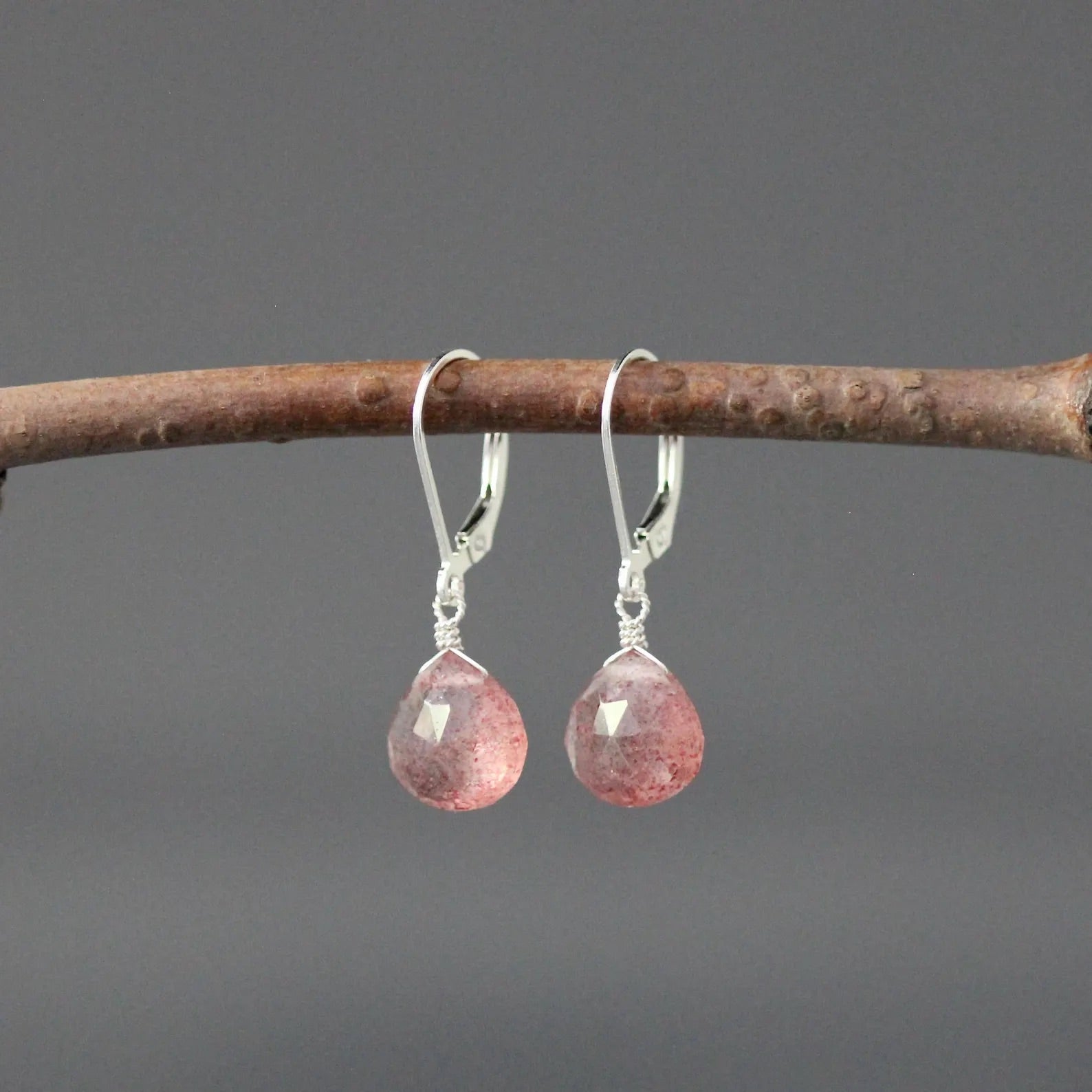 Strawberry quartz and silver earrings against a gray backdrop
