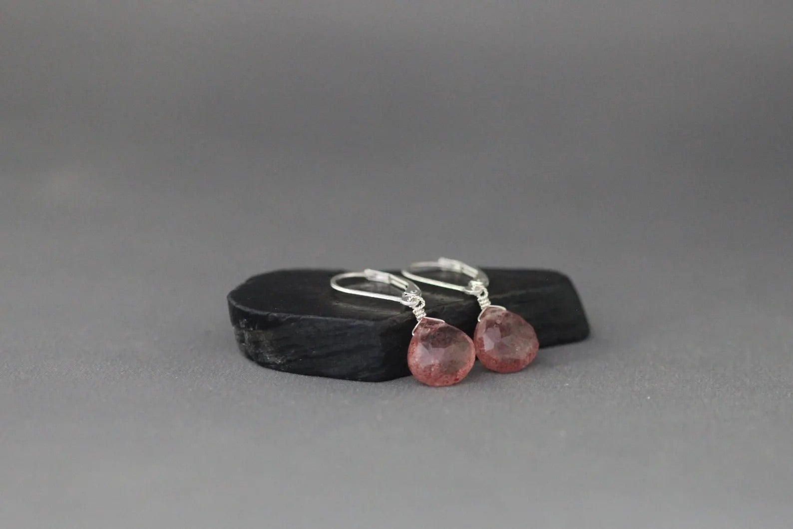 Strawberry quartz and silver earrings against a gray backdrop